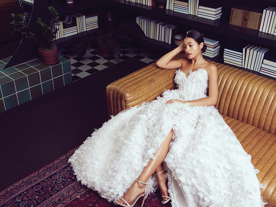 Bride lounging in library in butterfly applique Luly Yang “Butterfly Me to the Moon” gown.